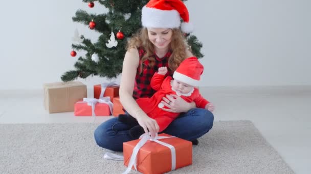 Familienurlaub und Weihnachtskonzept. junge Mutter mit Kind packt Weihnachtsgeschenk aus — Stockvideo