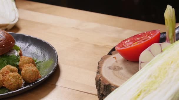 Leckerer Burger mit Falafel auf rustikalem Holz — Stockvideo