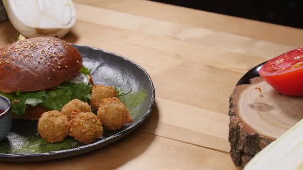 Hamburger savoureux avec falafel sur une surface en bois rustique — Video