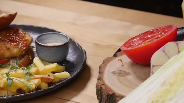Hambúrguer saboroso com batatas fritas em uma superfície de madeira rústica — Vídeo de Stock