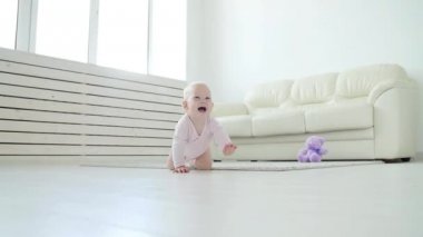 Sevimli bebek kız beyaz güneşli odada sürünmek öğrenme.
