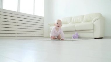 Sevimli bebek kız beyaz güneşli odada sürünmek öğrenme.