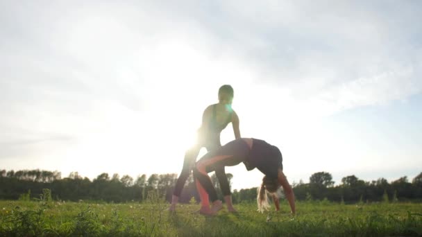 Allegro allenatore e donna positiva teletrasporto mentre fa un esercizio di stretching all'aperto al tramonto — Video Stock