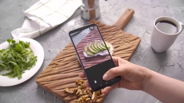 Gezond eten concept. Hand nemen van foto sandwich met avocado met smartphone — Stockvideo