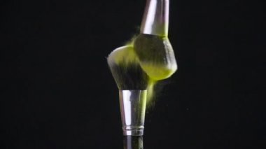 Güzellik konsepti. Siyah zemine yayılan altın kozmetik tozuyla kozmetik fırçası