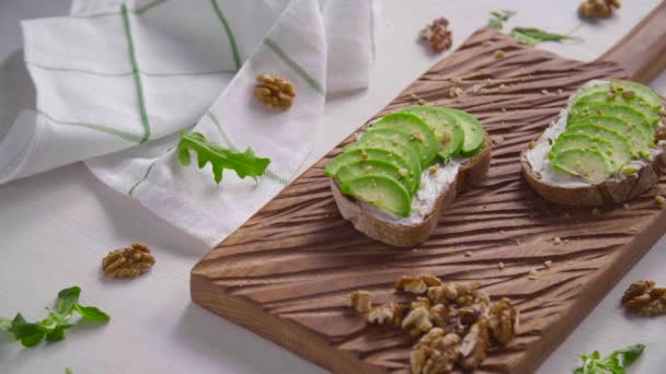 Concepto de alimentación saludable. Tostadas con crema de aguacate en la tabla de madera blanca — Vídeos de Stock