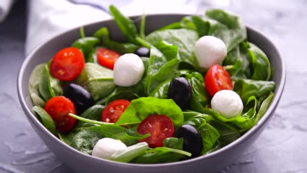 Вегетаріанська і органічна харчова концепція. Італійський або середземноморський салат. Tomato mozzarella basil листки чорні оливки і оливкова олія обертаються — стокове відео