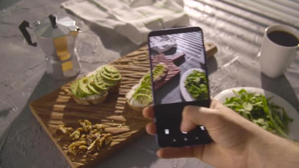 Gezond eten concept. Hand nemen van foto sandwich met avocado met smartphone — Stockvideo