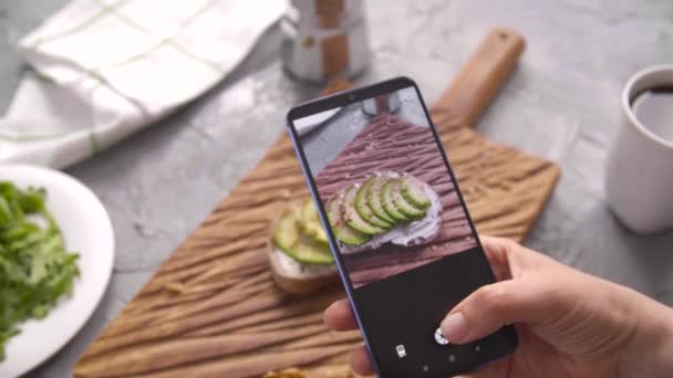 Gezond eten concept. Hand nemen van foto sandwich met avocado met smartphone — Stockvideo