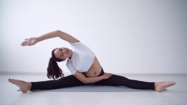 Concetto di salute. Giovane donna incinta fa esercizio di yoga nella stanza bianca — Video Stock