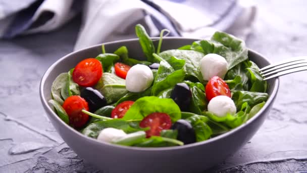 Вегетаріанська і органічна харчова концепція. Італійський або середземноморський салат. Tomato mozzarella basil листки чорні оливки і оливкова олія обертаються — стокове відео