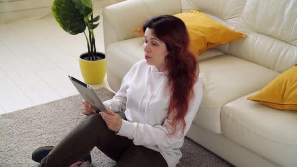 Concept d'isolement personnel. Jeune femme assise sur un canapé dans le salon et parlant par appel vidéo. — Video