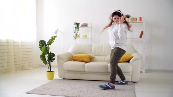 Víkend doma. Šťastná žena poslouchá hudbu a tančí v obývacím pokoji — Stock video