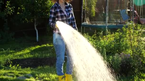 Mujer joven regando plantas en su jardín con manguera de jardín. Concepto Hobby — Vídeo de stock