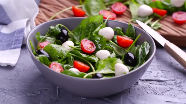 Vegetariano y, concepto de alimentos orgánicos. Ensalada Caprese italiana o mediterránea. Tomate mozzarella hojas de albahaca aceitunas negras y aceite de oliva rotar — Vídeo de stock