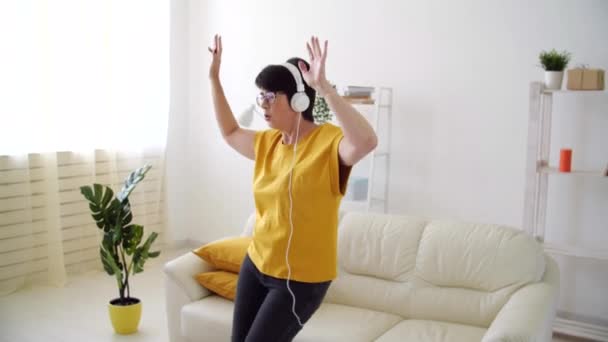Krásná seniorka uvolněná a tančící, poslouchající doma hudbu. — Stock video