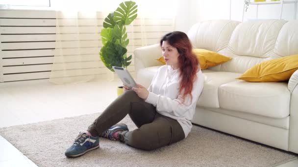 Zelfisolatie concept. Jonge vrouw zittend op een bank in de woonkamer en pratend via videogesprek. — Stockvideo