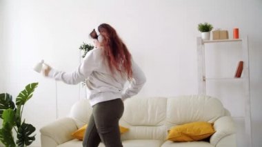 Oturma odasında müzik dinleyip dans eden mutlu bir kadın.