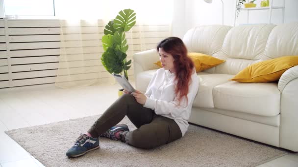 Zelfisolatie concept. Jonge vrouw zittend op een bank in de woonkamer en pratend via videogesprek. — Stockvideo