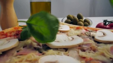 Fesleğen yaprakları pizzanın üstüne dökülüyor.