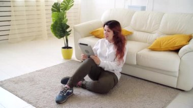 Kişisel izolasyon kavramı. Oturma odasındaki kanepede oturan ve video aracılığıyla konuşan genç bir kadın..