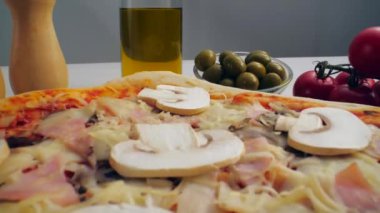 Fesleğen yaprakları pizzanın üstüne dökülüyor.