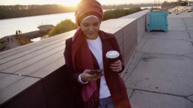 Genç Müslüman kadın tesettürlü, şehir dışında kahve molası veriyor.