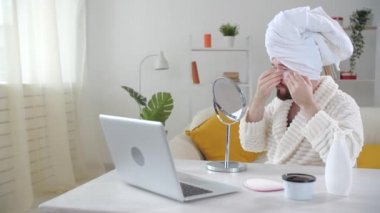 Deri tedavisi ve kişisel bakım konsepti. Gülümseyen genç adam evde göz maskesi takıyor.