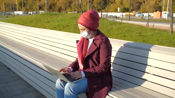 Ung muslimsk kvinna med laptop sitter på en parkbänk — Stockvideo