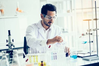 Laboratuvar araştırması için elinde test tüpleri tutan bir bilim adamı..