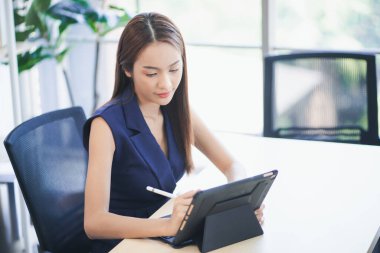 Asyalı kadın ofiste dizüstü bilgisayarda çalışmakla meşgul..