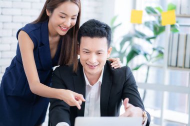 Modern ofiste dizüstü bilgisayarda çalışırken gülümseyen iş çifti