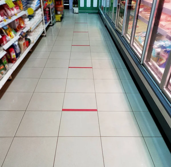 Social Distancing. Keep Your Distance. Marking on the floor of a Mini mart.COVID-19 safe social distancing practice.