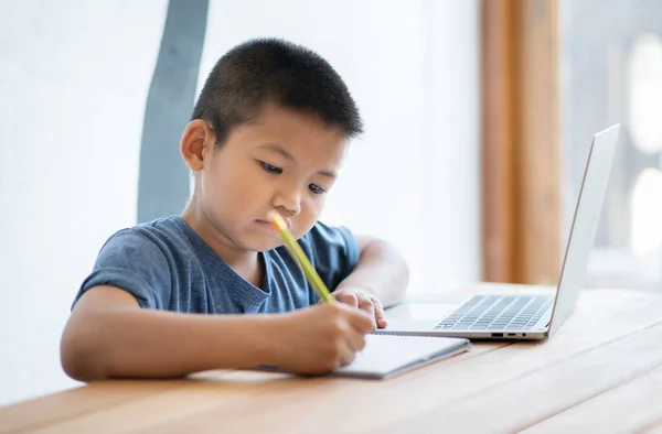 Asian boy learning online education at home with digital tablet and doing school homework. Kid using tablet for searching information on internet,E-learning online education.