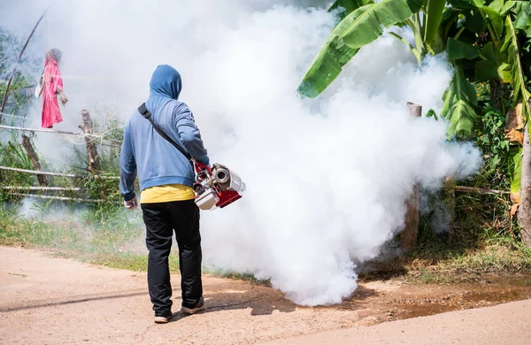 Worker fogging machine spraying smoke to eliminate mosquitoes.Prevention of epidemics in the rainy season and general location in community.