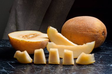 Olgun bütün ve yaz saati yarım honeydew kavun meyve. Olgun sulu kavun meyve karanlık mermer arka plan üzerine dilimlenmiş