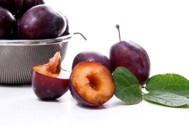 Tatlı sulu Erik, tam ve yarım olgun Erik yaprak beyaz bir arka plan üzerinde izole kevgir önünde çelik kevgir