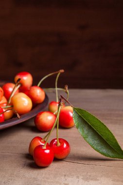 Kil plaka üzerinde vintage ahşap adam kiraz ağacının yaprak yeşil ile sarı tatlı kiraz ve çeşitli meyve çilek ile