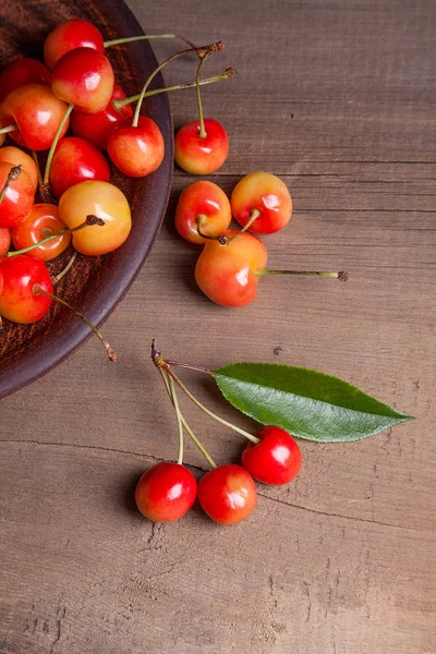Kil plaka üzerinde vintage ahşap adam kiraz ağacının yaprak yeşil ile sarı tatlı kiraz ve çeşitli meyve çilek ile