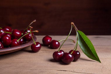 Kil plaka üzerinde vintage ahşap adam kiraz ağacının yaprak yeşil ile kırmızı tatlı kiraz ve çeşitli meyve çilek ile