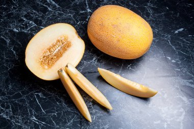 Olgun bütün ve yaz saati yarım honeydew kavun meyve. Olgun sulu kavun meyve karanlık mermer arka plan üzerine dilimlenmiş