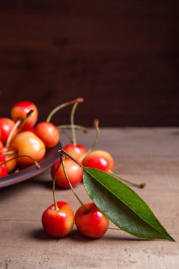 Kil plaka üzerinde vintage ahşap adam kiraz ağacının yaprak yeşil ile sarı tatlı kiraz ve çeşitli meyve çilek ile
