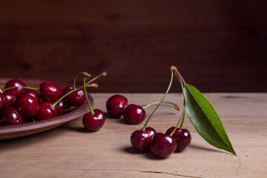 Kil plaka üzerinde vintage ahşap adam kiraz ağacının yaprak yeşil ile kırmızı tatlı kiraz ve çeşitli meyve çilek ile