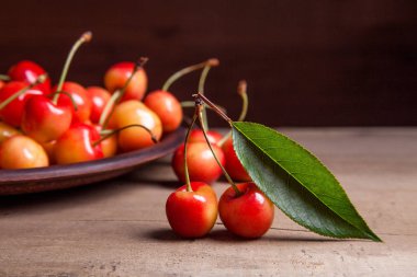 Kil plaka üzerinde vintage ahşap adam kiraz ağacının yaprak yeşil ile sarı tatlı kiraz ve çeşitli meyve çilek ile