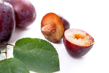 İki tam ve yarım tatlı sulu Erik ile beyaz bir arka plan üzerinde izole büyük yaprak yeşil