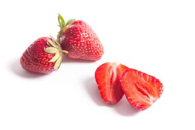Tatlı çilek yarım dilimlenmiş ve bütün berry ile. Beyaz arka plan üzerinde izole taze çiğ kırmızı meyveler