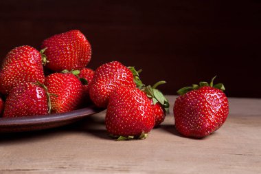 Tatlı çilek antika arka plan üzerinde. Ahşap arka plan üzerinde çilek taze Olgun kırmızı meyveler ile kil plaka