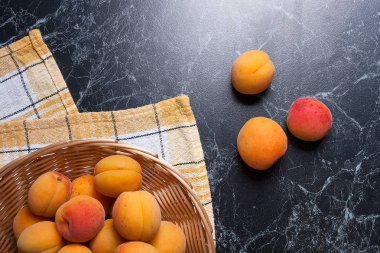 Olgun organik kayısı sarı ahşap sepet içinde. Rustik tarzı - organik kırmızı sulu kayısı karanlık mermer zemin üzerine vintage ahşap sepet içinde kompozisyon. Sağlıklı gıda kavramı. Hasat zamanı