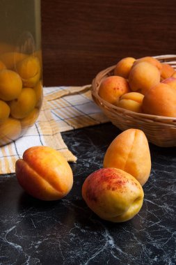 Tatlı Kayısı Kompostosu karanlık mermer üzerinde büyük cam kavanoz konserve ve yaz anda olgun organik kayısı hasat. Rustik tarzı - organik sarı sulu kayısı bütün ve yarıya sarı ahşap sepet ve ev yapımı Kayısı Kompostosu canne kompozisyon