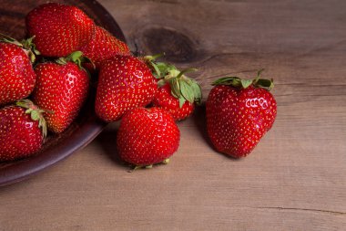 Tatlı çilek antika arka plan üzerinde. Ahşap arka plan üzerinde çilek taze Olgun kırmızı meyveler ile kil plaka